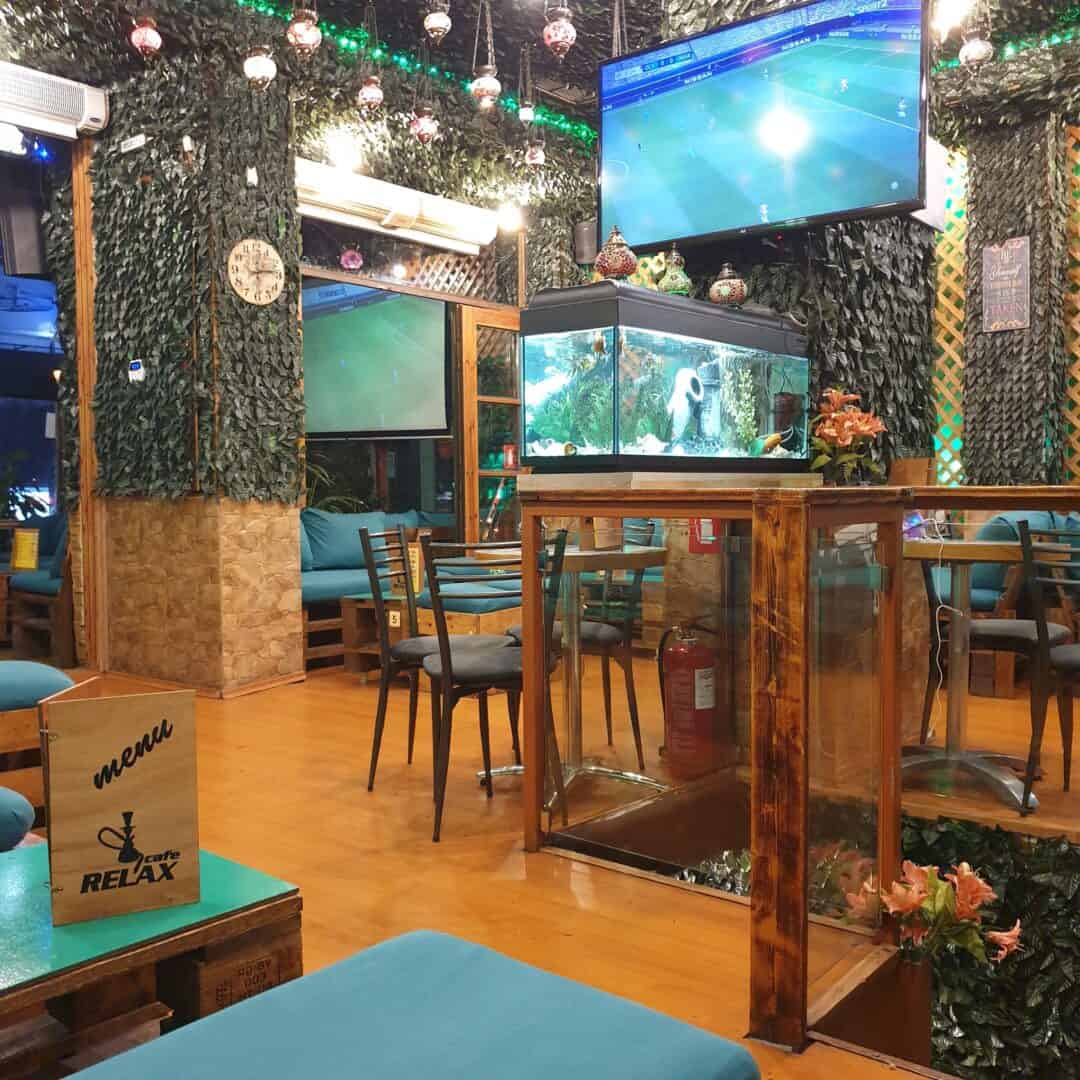 Cozy shisha lounge with aquarium, TV, and vibrant decor at Relax Cafe.