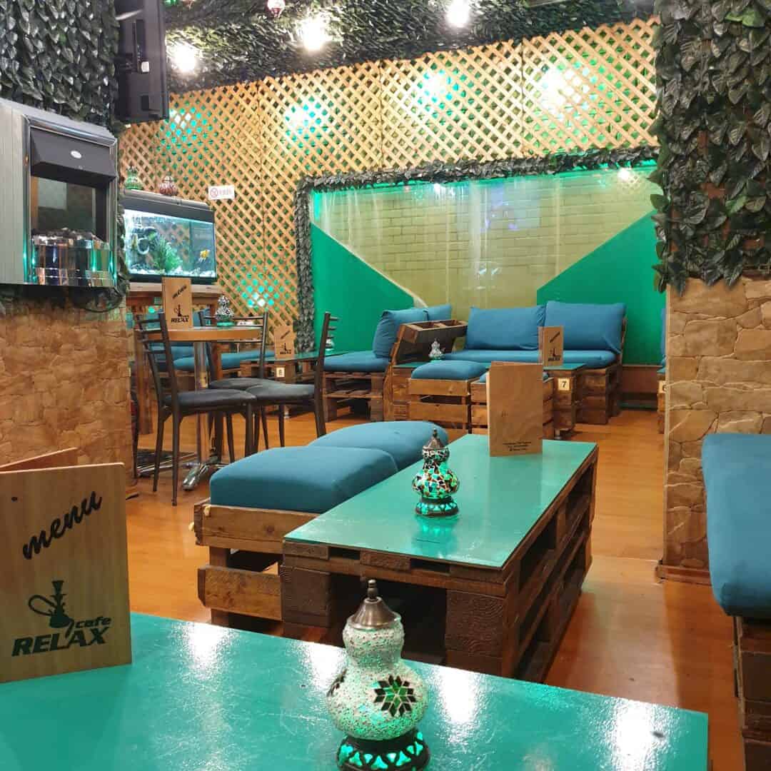 Cozy shisha lounge with wooden furniture and vibrant lighting at Relax Cafe.