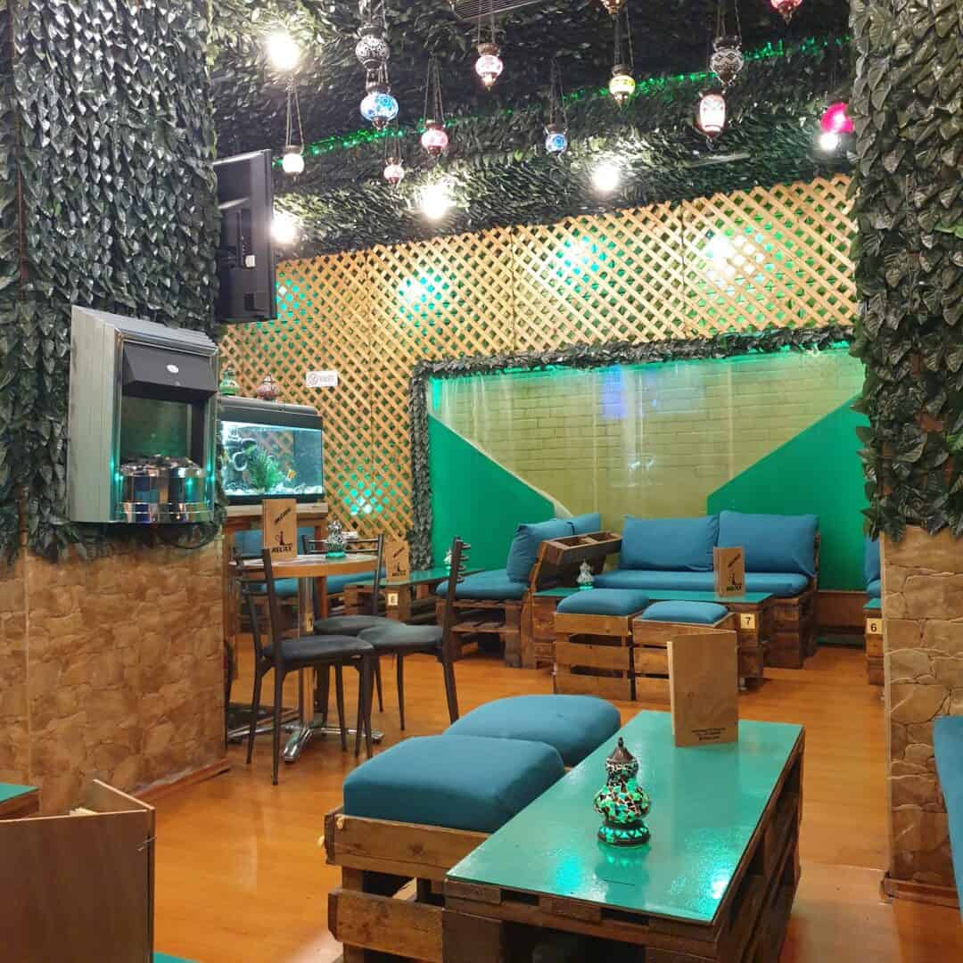 Cozy shisha lounge with wooden furniture and colorful hanging lights.