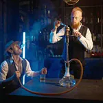 Two men enjoying shisha at a bar with blue lighting and smoke effects.